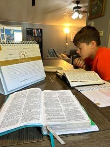 Homeschooler studying the bible at the dining room table