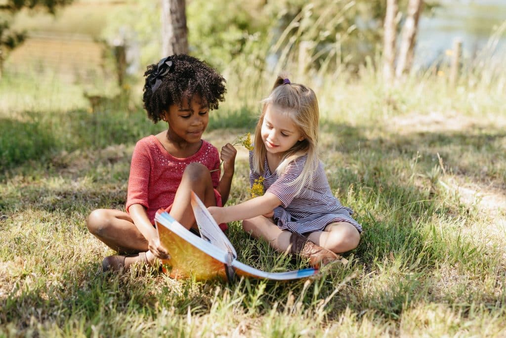 two preschool girls reading Exploring Creation Together: Preschool Science outside