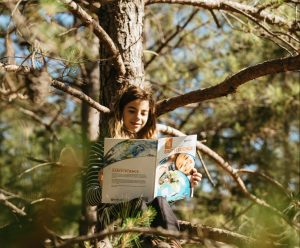 young girl reading in a tree